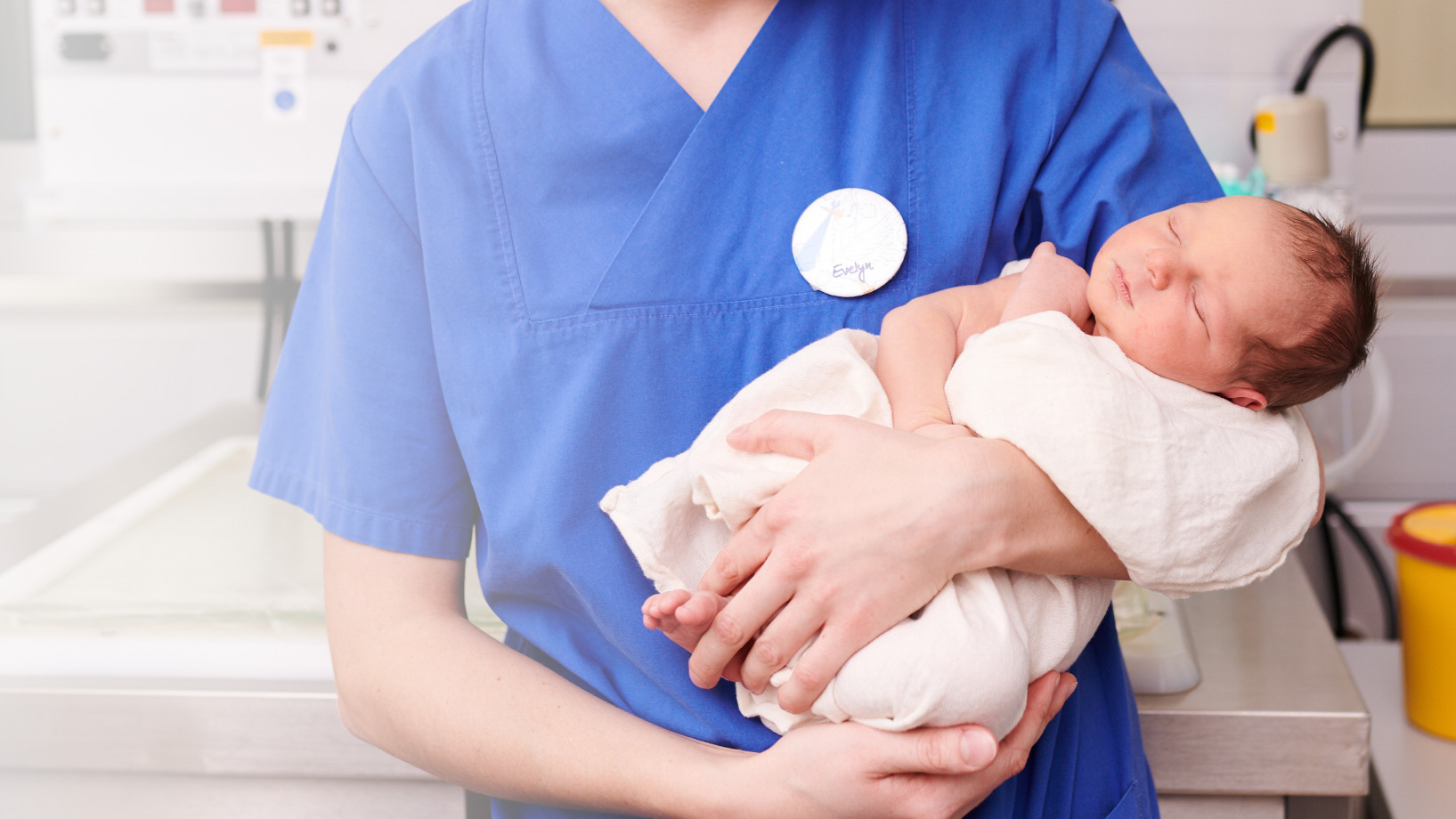 Eine Hebamme hält ein Neugeborenes im Arm